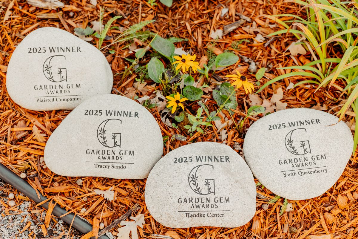 four stones laying on a bed of mulch, each stone is engraved with "2025 Winner" and "Garden Gem Awards" with the names of the winners etched below